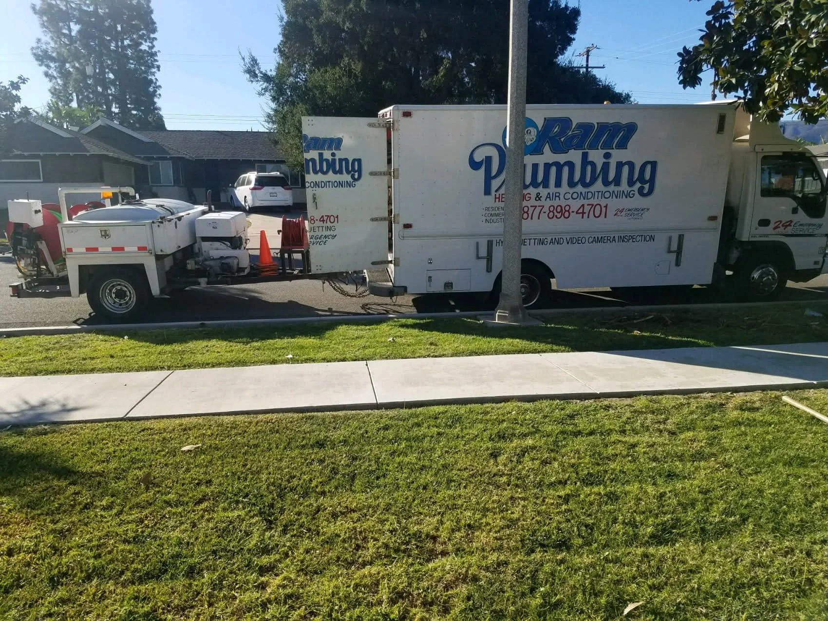 Service vehicles parked in residential driveway with plumbing and HVAC equipment