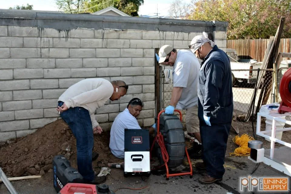 Four workers installing foundation drain system with sump pump at concrete block wall base