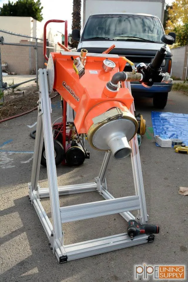 Orange pipe bursting machine on aluminum frame with hydraulic components and brass fittings