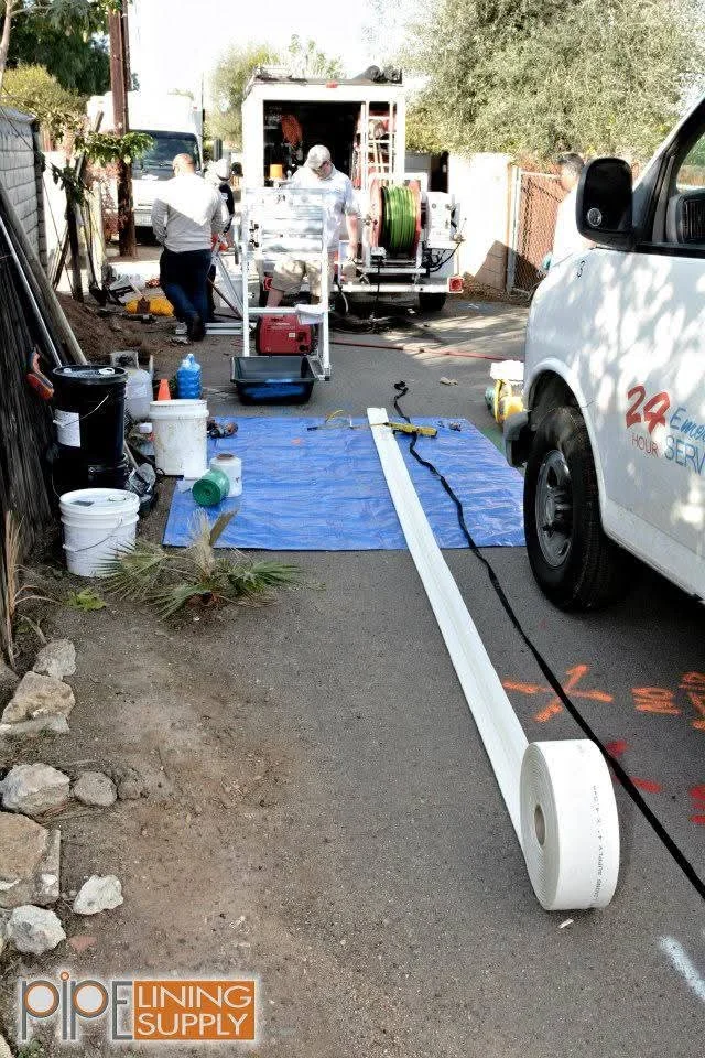 Sewer line installation with white PVC pipe, blue protective covering, and service equipment on residential property