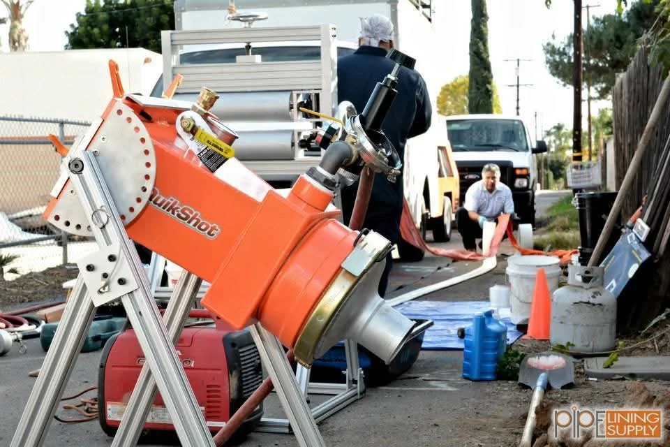 Orange pipe-bursting machine with pneumatic equipment on commercial job site