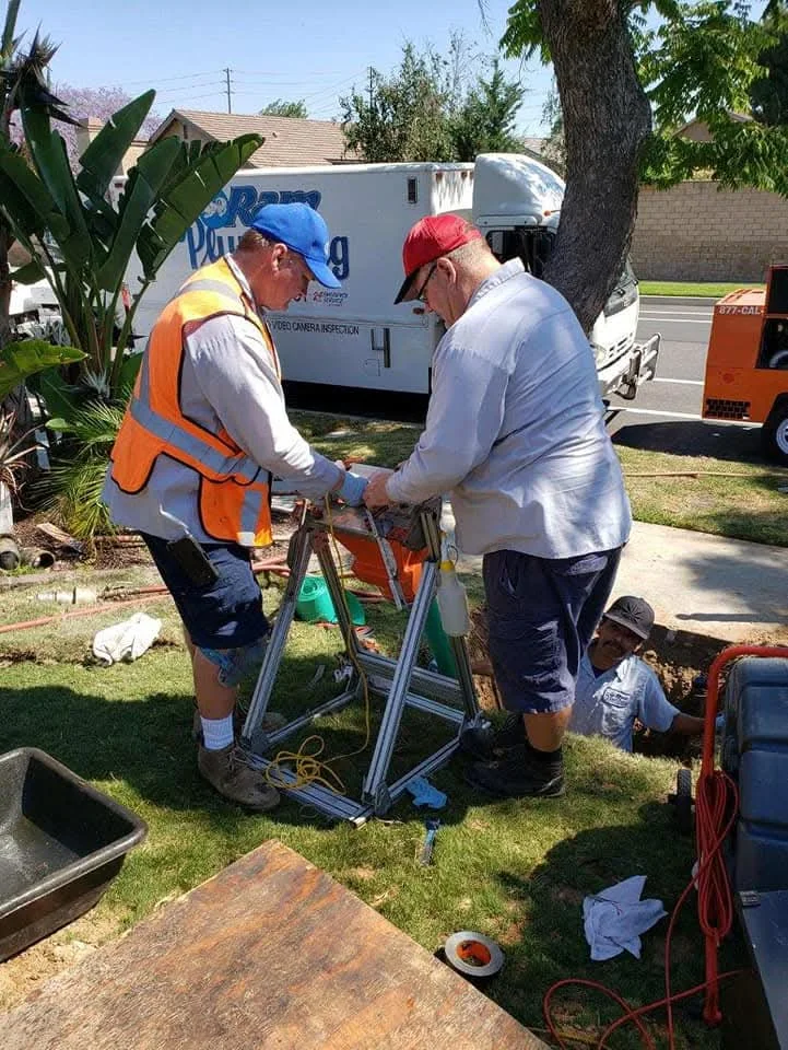 Plumbers conducting underground pipe inspection with camera equipment and diagnostic tools